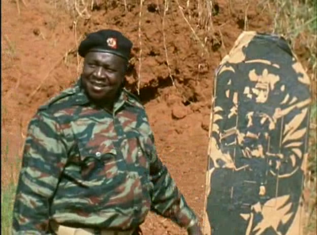 Amin na pozadí tradičního afrického štítu.