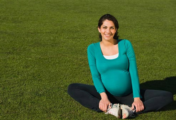 donna incinta che si siede sul prato